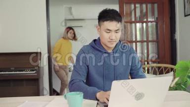 年轻的亚洲夫妇管理财务，在现代家庭使用笔记本电脑和计算器审查他们的银行账户。